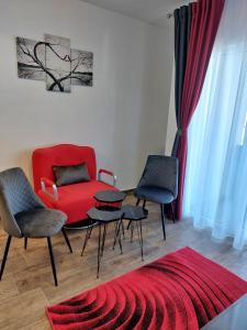 uma sala de estar com um sofá vermelho e duas cadeiras em Garsoniera Carmina em Techirghiol