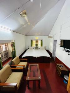 ein Schlafzimmer mit einem Bett, einem Sofa und einem Tisch in der Unterkunft Coorg Daffodil Guesthouse in Madikeri
