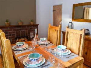 a wooden table with plates and wine glasses on it at Daisy Cottage in Sea Palling