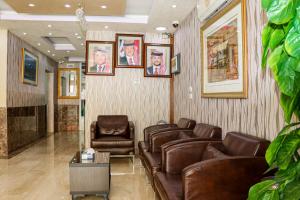 - une salle d'attente avec des fauteuils en cuir et des portraits sur le mur dans l'établissement Al Jamal Suites, à Amman