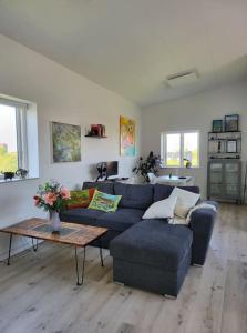a living room with a blue couch and a table at Solrig og moderne villalejlighed tæt på midtbyen 