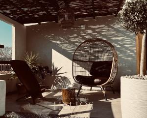 a rattan chair sitting on a patio with plants at Jacuzzi Vue sur Mer Helios Suite & Spa in Saint-Cyr-sur-Mer