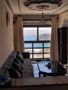 a living room with a couch and a table and a large window at Al-marsa2 in Al Hoceïma