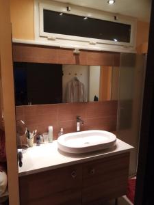 La salle de bains est pourvue d'un lavabo et d'un grand miroir. dans l'établissement villa rahuette, à Sète