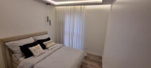 Un dormitorio con una cama con sábanas y almohadas blancas. en Apartment Zamkowa Park, en Węgorzewo