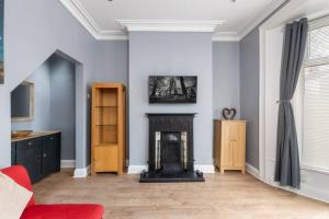 a living room with a fireplace and a red couch at Large Parade Coastal House in Hartlepool