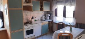 eine Küche mit weißen Geräten und einem Tisch darin in der Unterkunft Ferienhaus in der Hansestadt mit Blick auf Ostsee in Wismar