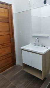 een badkamer met een wastafel en een houten deur bij Alquiler por dia Departamento 3 personas Gral Roca Casita Artigas in General Roca