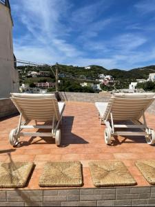 two lounge chairs on a patio with a view of a city at Casa Santa Maria - Suite Mediterraneo in Ponza