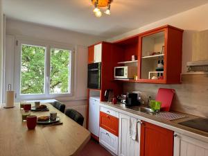 uma cozinha com armários vermelhos e uma mesa de madeira em Royale London Signature * * * * * em Annemasse