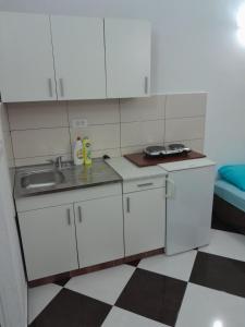 een kleine keuken met witte kasten en een wastafel bij Apartments Neda in Sutomore
