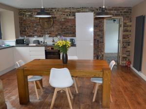 a kitchen with a wooden table and white chairs at Home Farm - The Dairy -uk34626 in Dunragit