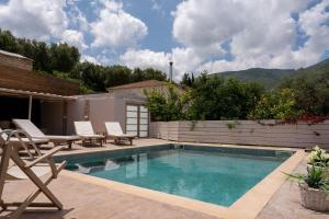 a swimming pool with two chairs and a table at Casa Di Terra in Pigadhákia