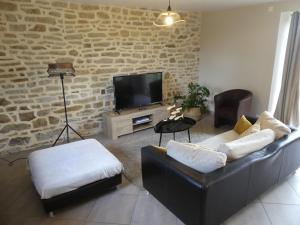 ein Wohnzimmer mit einem Sofa und einem TV in der Unterkunft Espace Acu-Nature in Saint-Évarzec