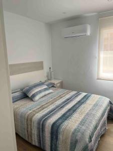 a bedroom with a large bed with a striped blanket at Apartamento con preciosas vistas a pie de playa in Santa Pola