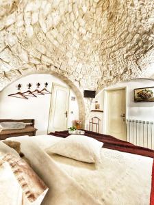 - une chambre avec un grand lit et un mur en pierre dans l'établissement Trulli Caroli, à Locorotondo