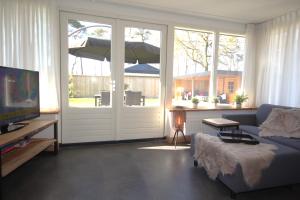 a living room with a couch and an umbrella at Bungalow Bavelds Home - Denekamp in Denekamp