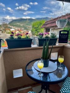 two glasses of orange juice on a table on a balcony at Lotus Apartment in Sarajevo