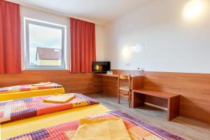 BisambergにあるOEKOTEL Korneuburgのベッド2台、デスク、テレビが備わる客室です。