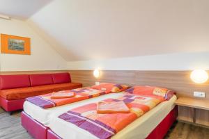 2 Betten in einem Zimmer mit Sofa in der Unterkunft OEKOTEL Korneuburg in Bisamberg