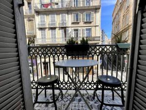 einen Tisch und zwei Hocker auf einem Balkon mit einem Gebäude in der Unterkunft T2 balcon Hyper centre - Paradis in Marseille