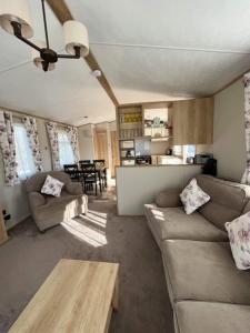 a living room with couches and a table and a kitchen at 3 bed luxury lodge at Hoburne Devon Bay in Goodrington
