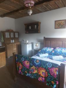 a bedroom with a bed with a flowered blanket and a refrigerator at Agroturystyka LipoweWzgórze- Jaś&Małgosia in Tereszpol