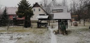 einen schneebedeckten Hof mit einem Haus und einem Vogelfutter in der Unterkunft Casa de oaspeți Csomortáni vendégház in Şoimeni