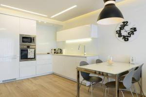 TLV Luxury Modern Apartment City Center في تل أبيب: مطبخ مع دواليب بيضاء وطاولة وكراسي
