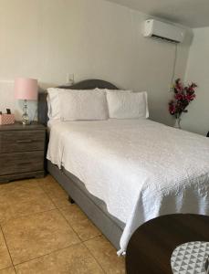 1 dormitorio con 1 cama y mesita de noche con colcha blanca en Cozy Studio…With Private Entrance en Las Vegas