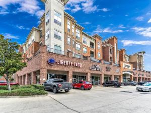 a large brick building with cars parked in a parking lot at Elegant 2BR Ideal for Long Term Stay in Houston