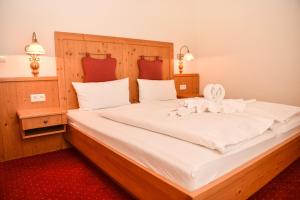 a bedroom with a large white bed with a wooden headboard at Aparthotel Sonnenburg in Schluchsee