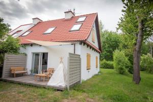 Casa blanca pequeña con terraza de madera en Domek Mikołajki, en Mikołajki