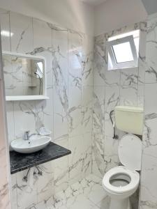 ein weißes Bad mit einem WC und einem Waschbecken in der Unterkunft Kastrati Apartments in Ulcinj