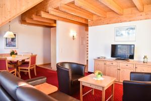 a living room with a couch and a tv and a table at Aparthotel Sonnenburg in Schluchsee