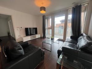 a living room with a black couch and a tv at Modern 2BR 2BA Apt wParking Sleeps 6 Comfortably in London