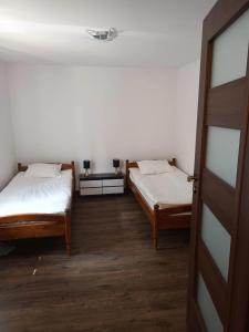 two beds in a small room with a door at Sielski Zakątek in Srokowo