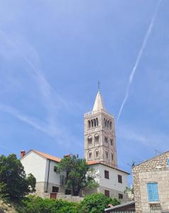una torre alta con una cruz en la parte superior de un edificio en Old town rooms, en Rab