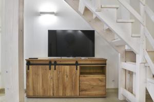 TV de pantalla plana en un armario de madera bajo una escalera en Vico Cialdini, en Salice Salentino