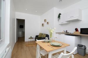uma cozinha e sala de estar com mesa e cadeiras em Charmant Studio à 10 min de la gare em Saint-Quentin