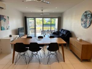 cocina y sala de estar con mesa de madera y sillas en Lovely 3 Bedroom Condo with Pool en Darwin