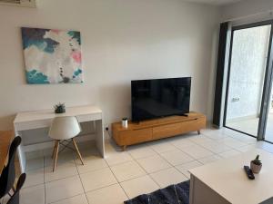 a living room with a flat screen tv and a desk at Lovely 3 Bedroom Condo with Pool in Darwin
