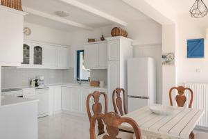 リクスリオンにあるVilla Afroditeの白いキャビネット、テーブルと椅子付きのキッチンが備わります。