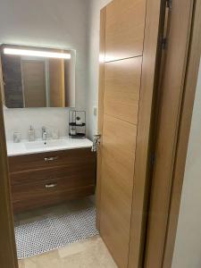 uma casa de banho com um lavatório e uma porta de madeira em Appartement de luxe sur agadir bay em Agadir