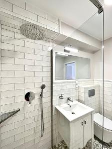 La salle de bains blanche est pourvue d'un lavabo et d'une douche. dans l'établissement Willa Mandala, à Dziwnówek