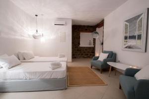 a white room with two beds and a table and chairs at Villa Anatoli in Mýkonos City