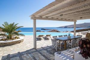a patio with a table and chairs and the ocean at Villa Anatoli in Mýkonos City