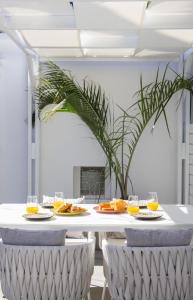 Biały stół z talerzami jedzenia i szklankami soku pomarańczowego w obiekcie 30villa Rd Studio w mieście Rodos