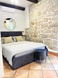 a bed in a room with a stone wall at Apartments Papilon in Vrsar