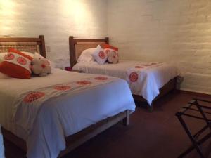 Duas camas num quarto com almofadas brancas e vermelhas em Hermosa Casa Tipica en Malinalco em Malinalco